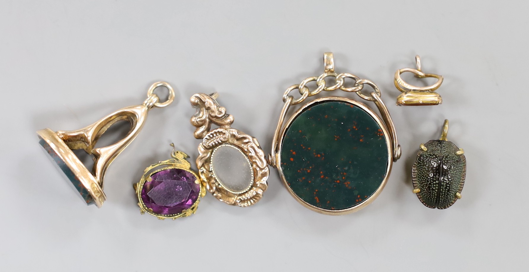 A late Victorian 9ct gold mounted carnelian and bloodstone set spinning fob seal, diameter 23mm, a later 9ct gold and bloodstone fob seal and four other items.